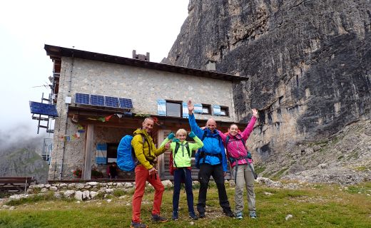 Twee volwassenen en twee kinderen voor een berghut