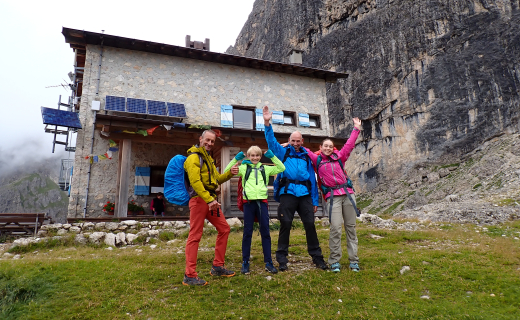 Twee volwassenen en twee kinderen voor een berghut