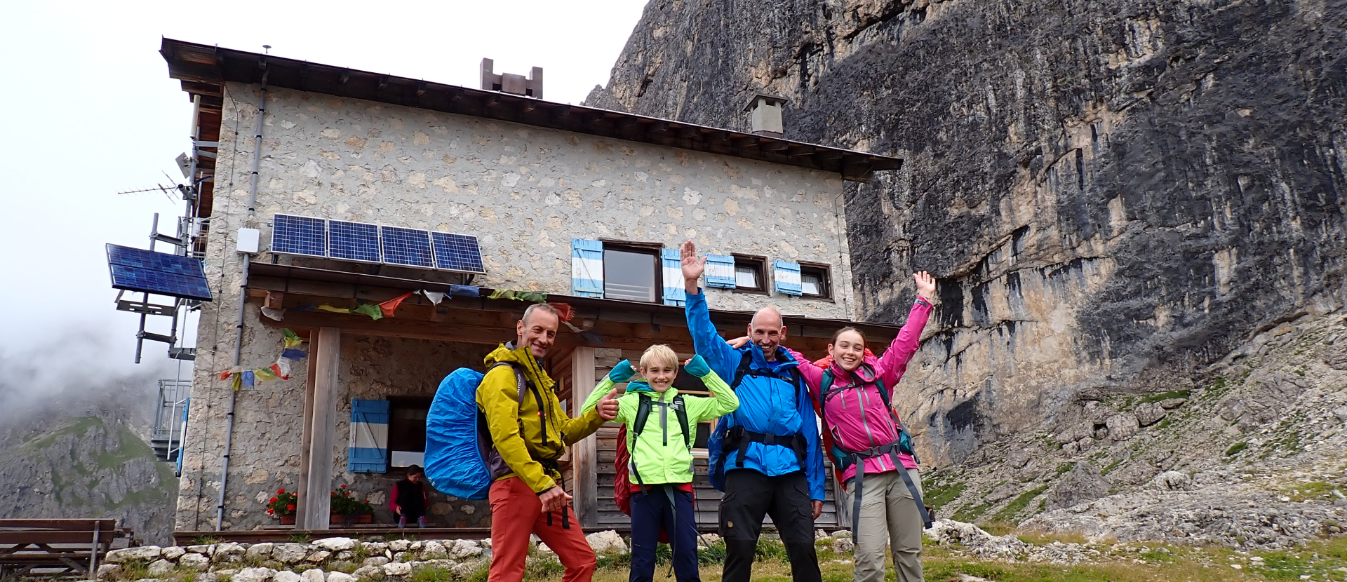 Twee volwassenen en twee kinderen voor een berghut
