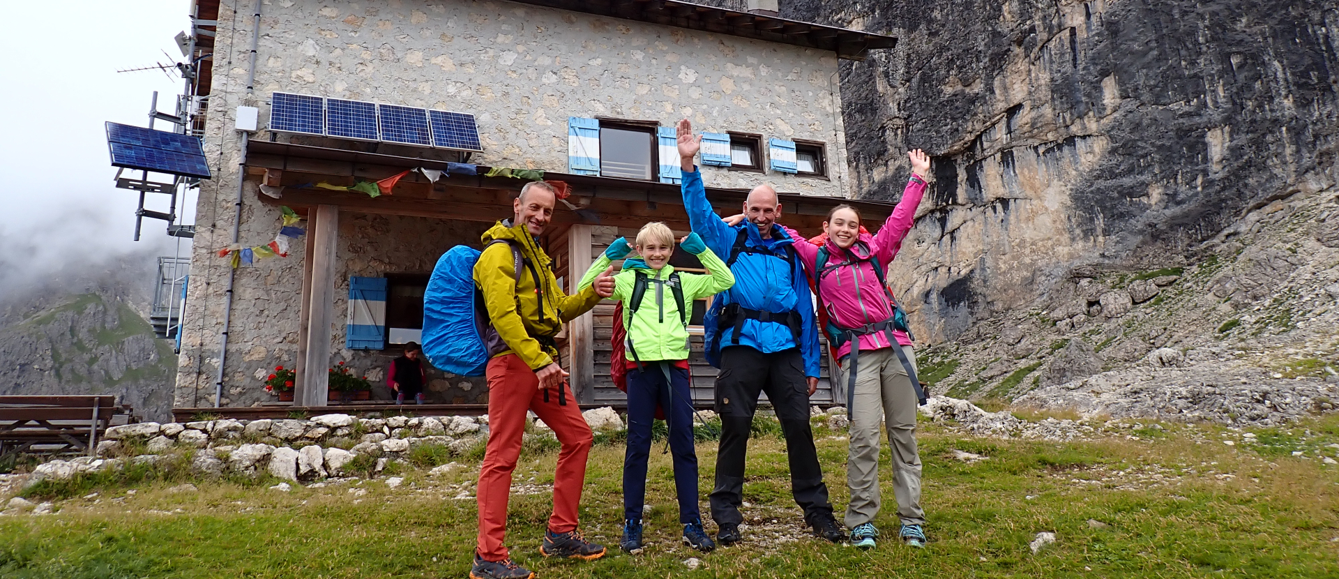 Twee volwassenen en twee kinderen voor een berghut