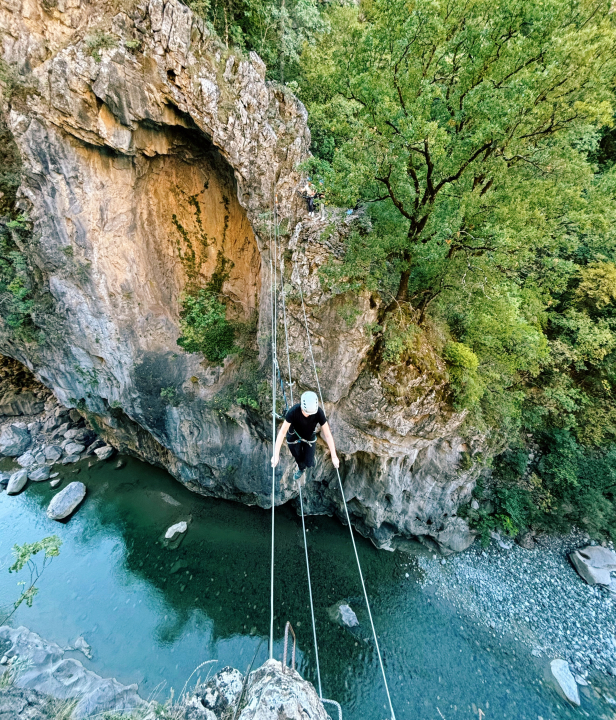 Blauwe rivier met daarboven staalkabels waar iemand overheen balanceert