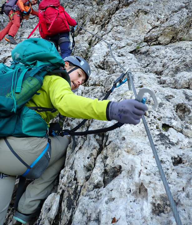 Persoon die aan het bergbeklimmen is langs een stalen kabel (via ferrata)