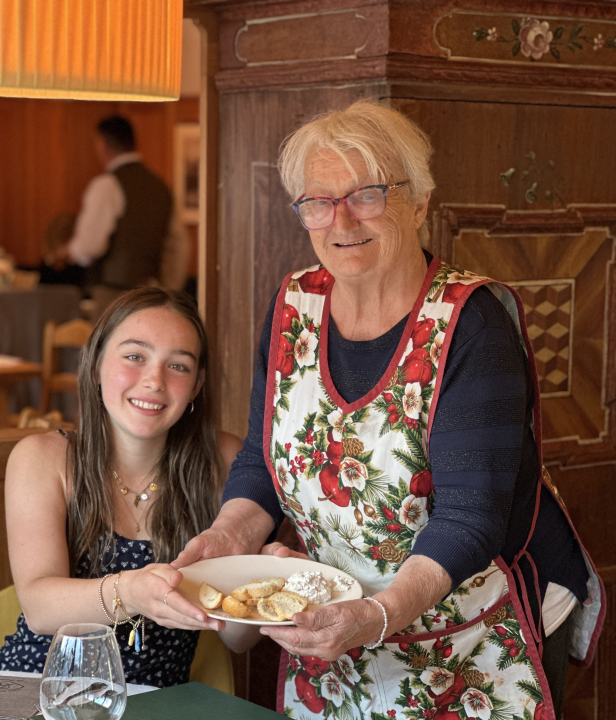 Oudere dame naast een meisje met een bord met eten in hun handen