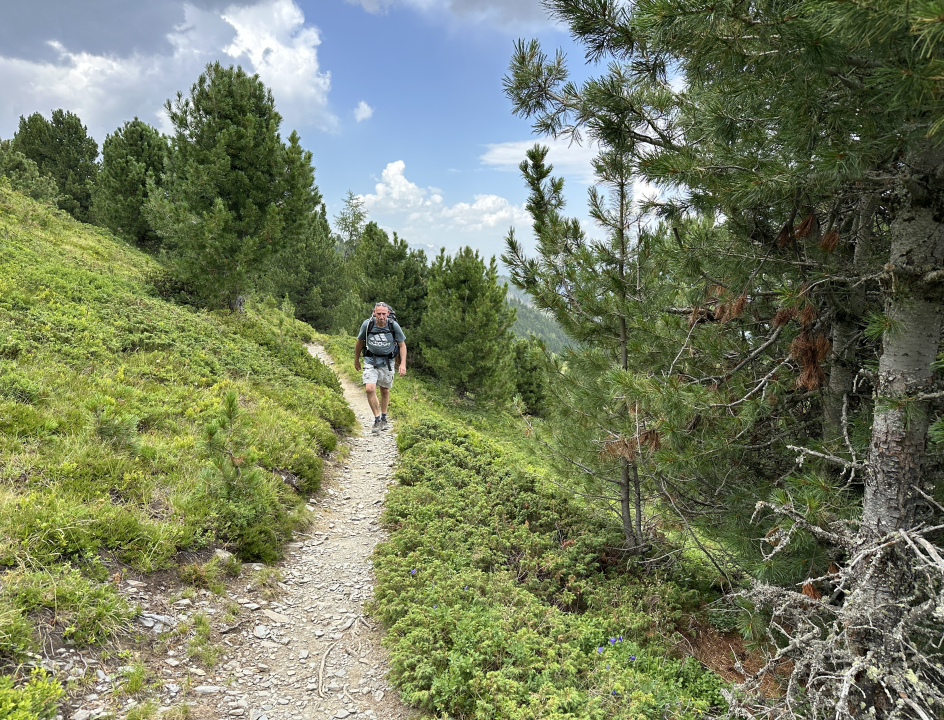 Man die naar je toe wandelt over een smal paadje in de bergen