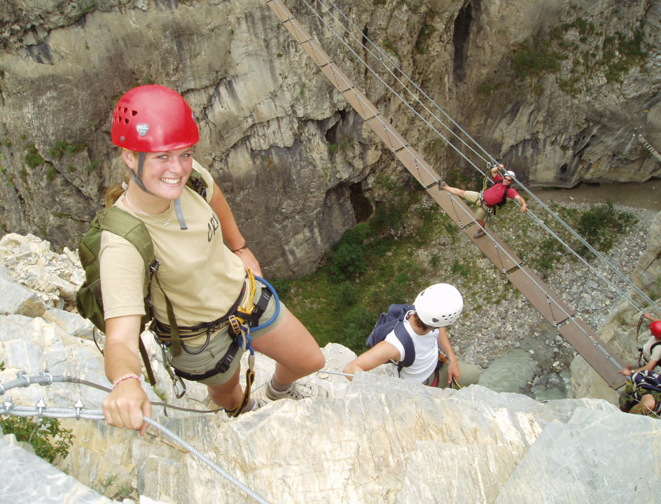 klimmers die over een brug lopen waarbij ze gezekerd zijn aan een staalkabel