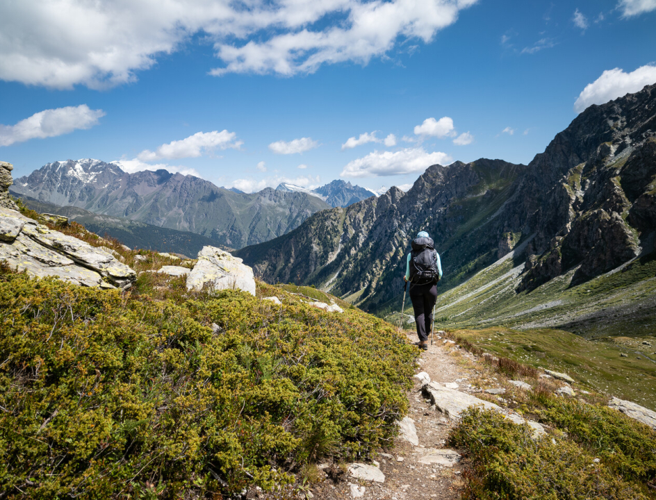 Iemand die met rugzak op door de bergen loopt over een smal paadje