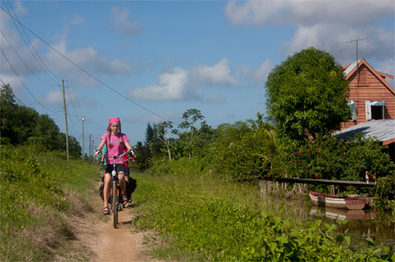 Meisje fietst door jungle van Suriname
