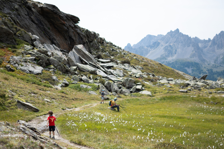 Twee kinderen en 1 volwassene op een wandelpad door de bergen