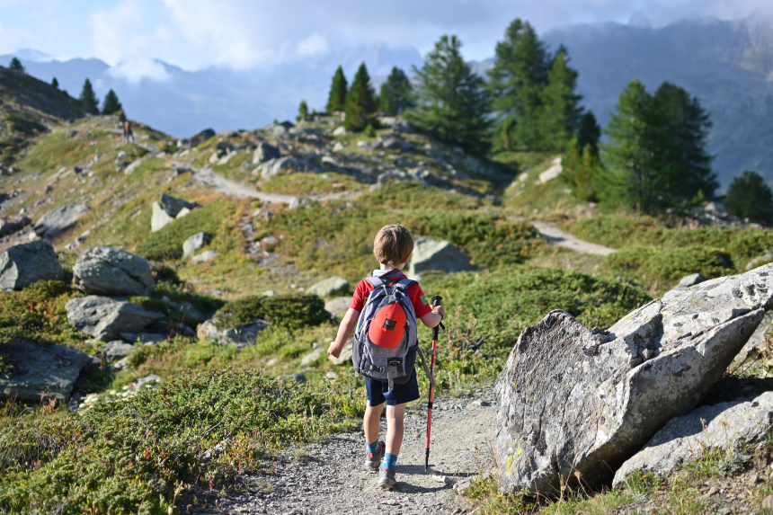 Klein kind met rugzak op, wandelt in de bergen