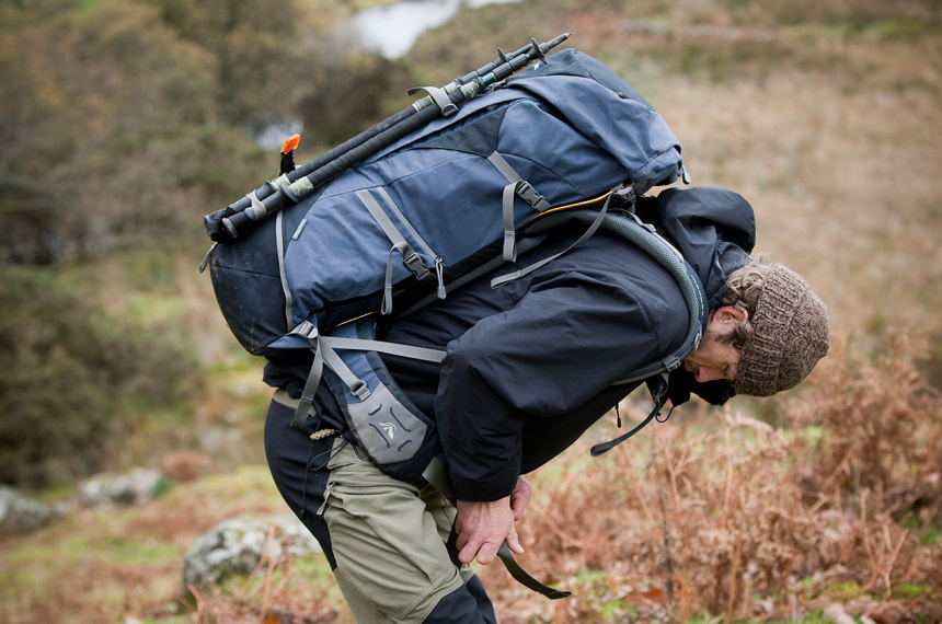 Buig voorover en schuif de rugzak hoog op de rug, zodat de heupbanden net boven heuphoogte zitten.
